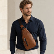 Homme en chemise bleu marine portant le sac bandoulière marron
