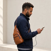 Homme portant la sacoche bandoulière marron en travers du buste, téléphone en main